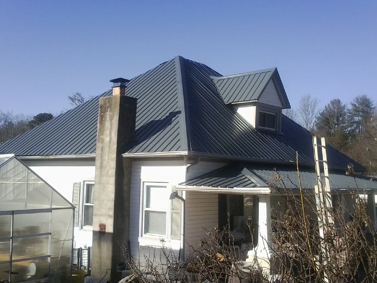 Dark blue standing seam metal roof on a white farmhouse with dormer — Slate & Tile Roof Repair by Roofing Brothers in Center Tuftonboro