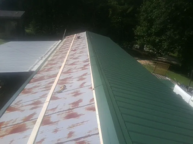 Old rusted panels beside newly installed green metal roofing — Wind Damage Roof Repair by Roofing Brothers in Center Tuftonboro