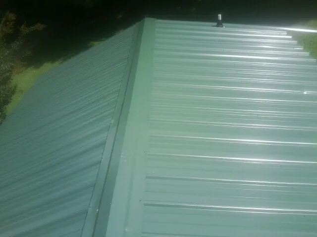 New green metal panels meeting at the ridge of a roof in Center Tuftonboro