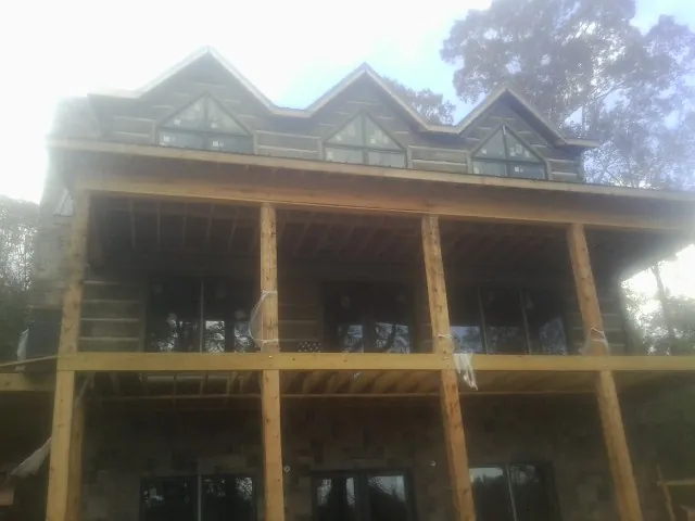 Dormers and porch framing on a large log home under construction — Roof Coating work by our crew in Center Tuftonboro