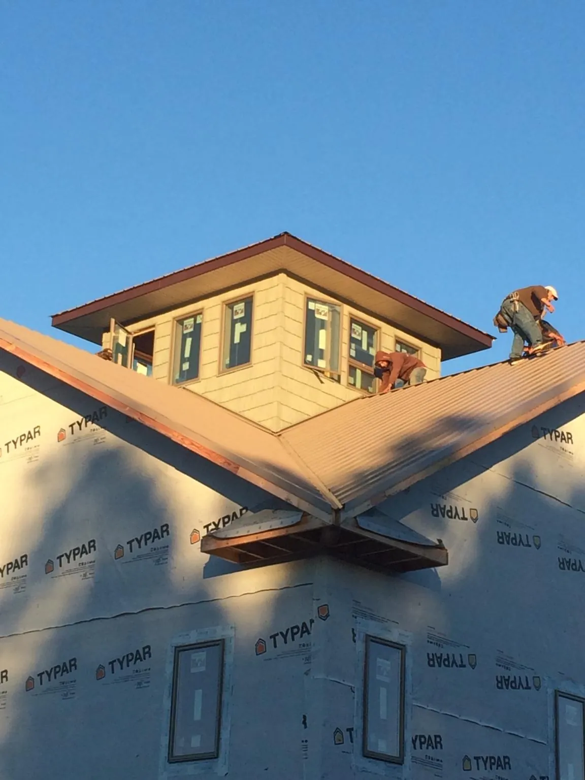 Roofers working around a rooftop cupola on a new metal roof at sunset — Roof Waterproofing in Center Tuftonboro by Roofing Brothers